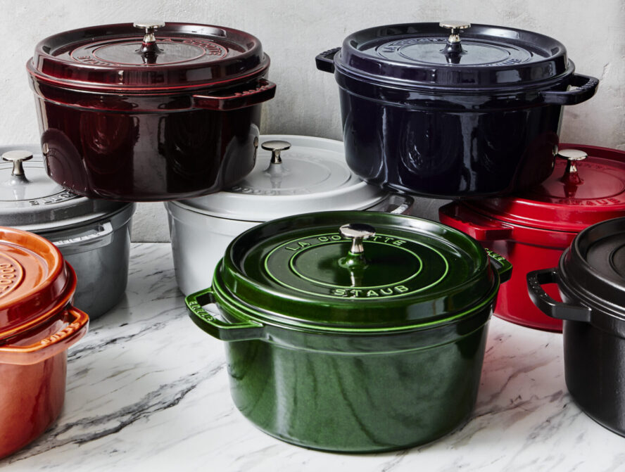 Image of several classic Staub Dutch ovens in various colors stacked on top of each other.