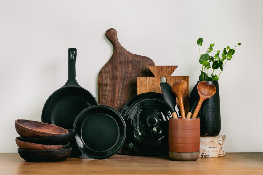 Image of several pieces of Xtrema pure ceramic cookware and wooden butcher blocks leaning against a wall in a kitchen.