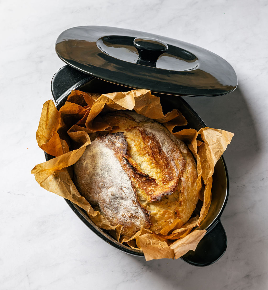 Image of the Xtrema Oval Dutch oven with parchment paper and a full loaf of sourdough bread.