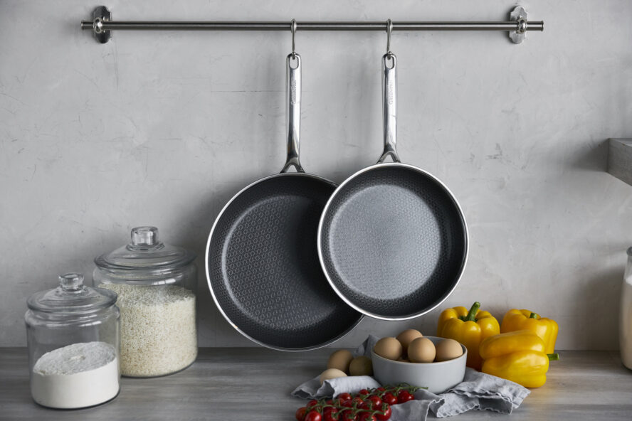 Image of two of the GreenPan Spectra Hybrid frypans included in this three-piece set, hanging in a brightly lit kitchen.