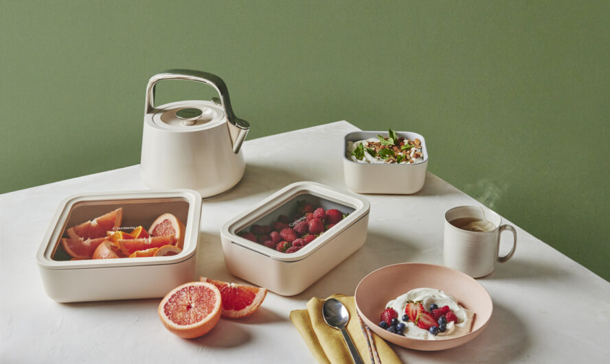 Image of the Caraway Food Storage set in cream on a table holding an arrangement of cut fruits.