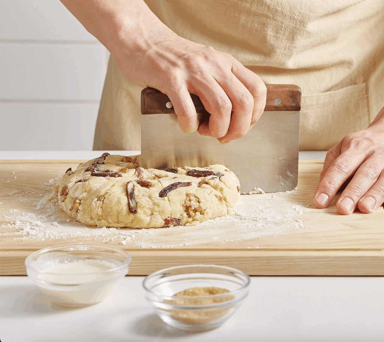 Image of the Misen Bench Scraper being used to slice bread dough on a butcher block.
