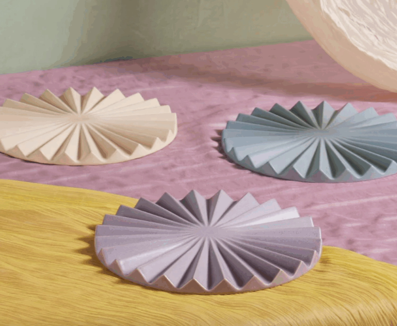 Image of three Our Place trivets in multiple colors displayed on a colorful tablecloth.