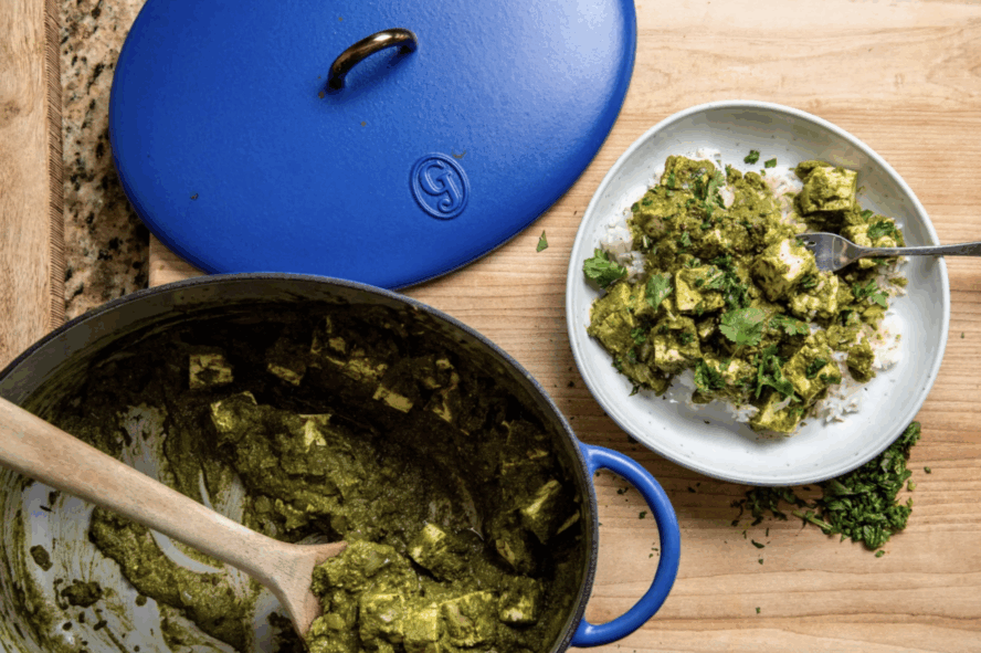 Image of the Great Jones Dutchess Dutch oven in the color Blueberry, being used to cook a saag paneer.