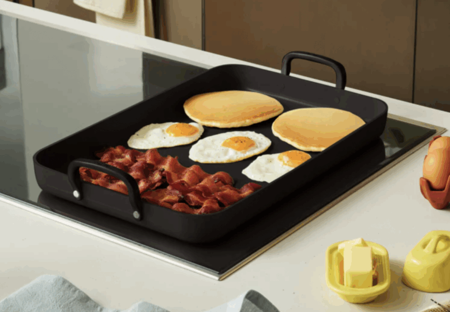 Image of the Our Place Essentials Griddle Pan being used to fry up a hearty breakfast with pancakes, eggs, and bacon.