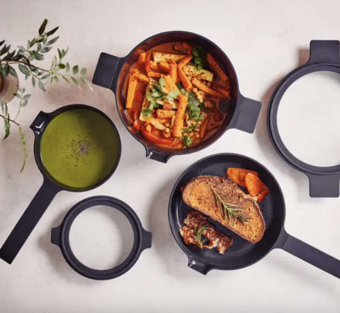 Image of the Alva Cookware Neat 5-Piece Nesting Set shown on a countertop with various soups and roasted dishes.