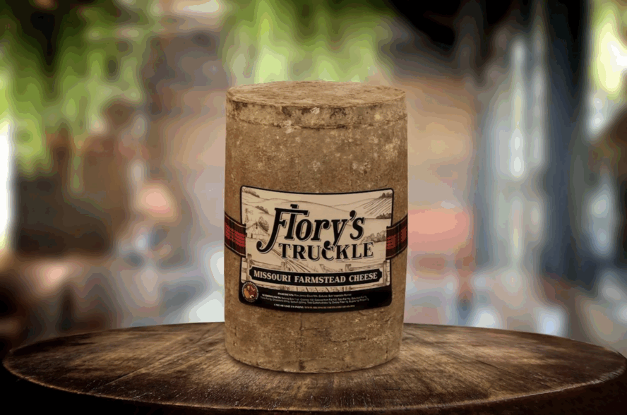 Image of a large wrapped cylinder of Flory's Truckle cheese from Milton Creamery in Missouri.