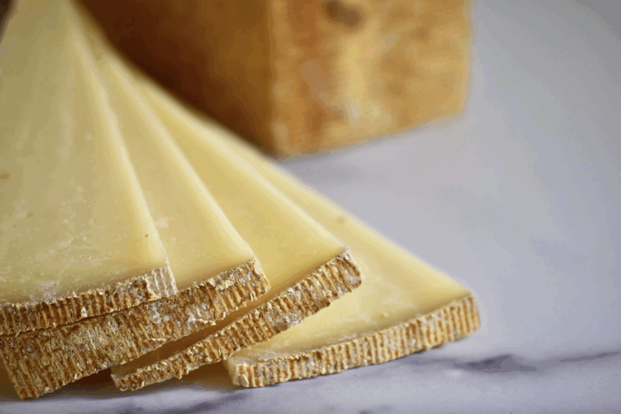 Image of several slices of Alpha Tolman cheese spread out in a fan-shape.