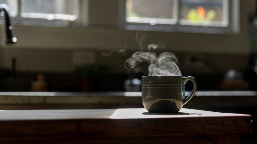 Image of a mug of hot decaf coffee on a kitchen counter, with steam rising out of the mug.