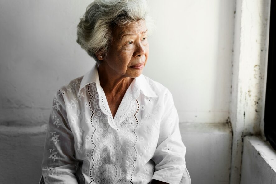 Image of an elderly Asian woman with white hair wearing a white collared shirt.