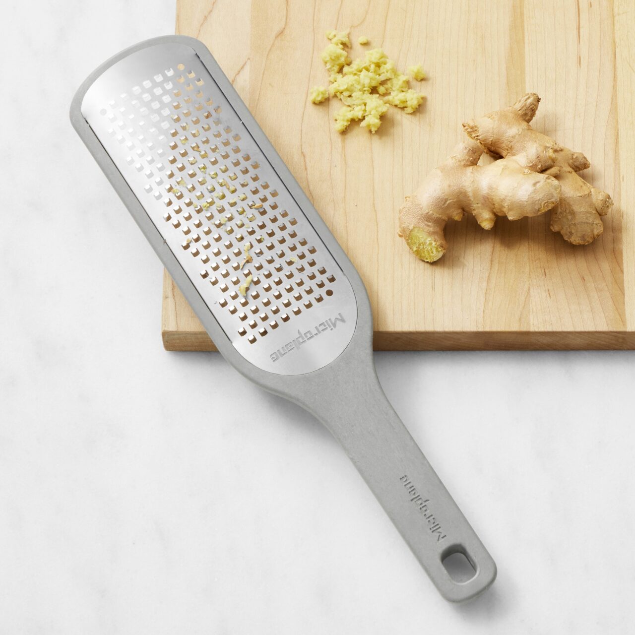 Image of a Microplane Eco Handheld Grater from Williams Sonoma, being used to grate ginger.
