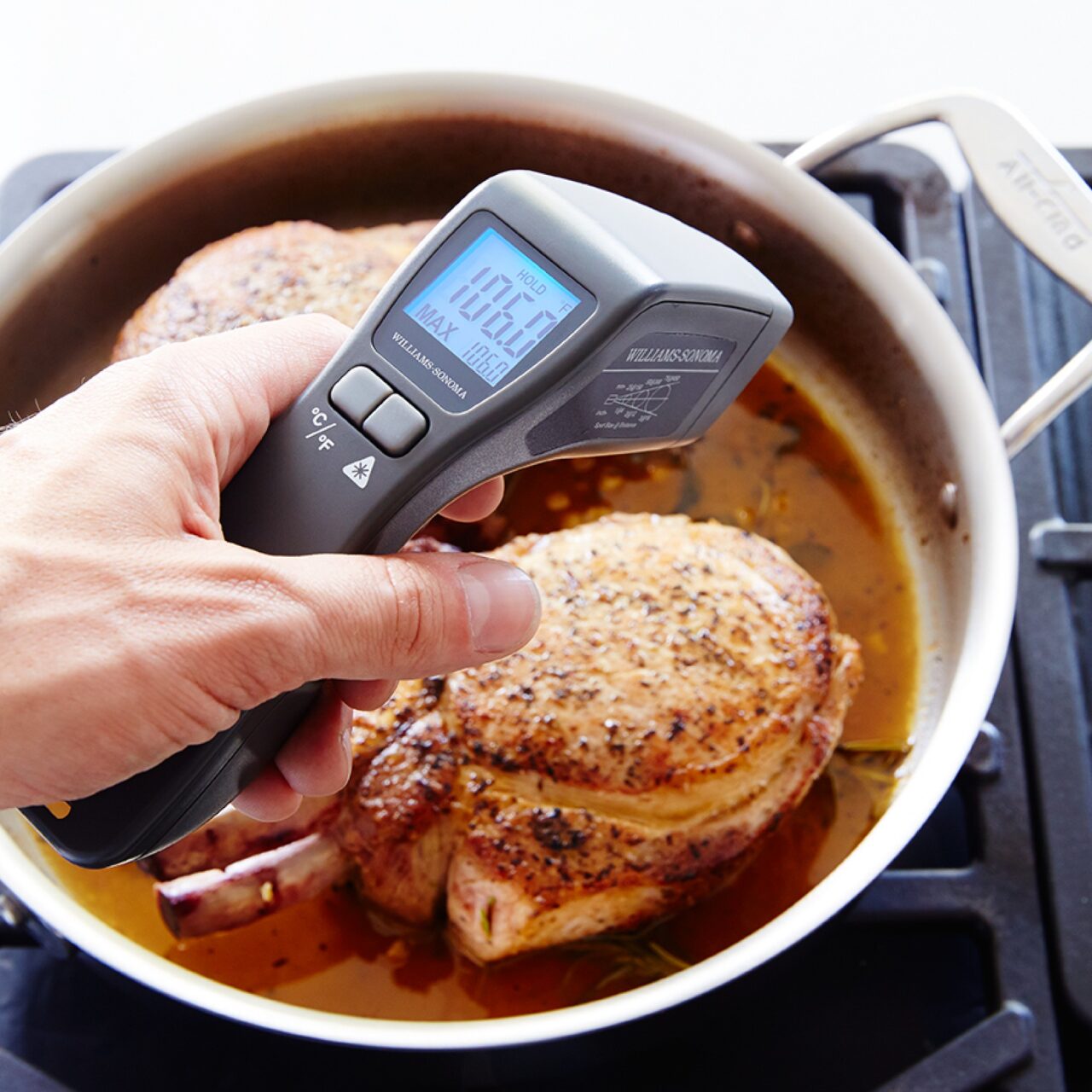 Image of the Williams Sonoma infrared thermometer held over a pot with a whole chicken, reading the temperature.