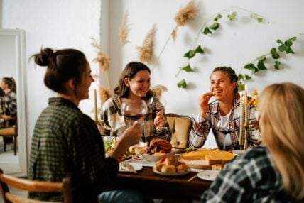 Image of several women sitting around a table enjoying Thanksgiving dinner together.