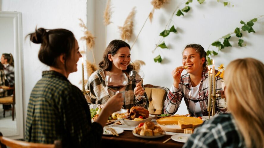 Image of several women sitting around a table enjoying Thanksgiving dinner together.