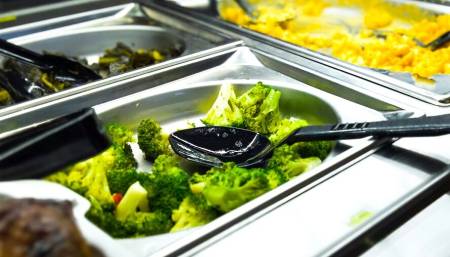 Image of a school lunch style vat filled with steamed broccoli.