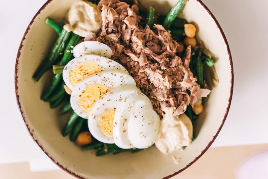Image of a bowl filled with green beans, hard-boiled eggs, and tuna.