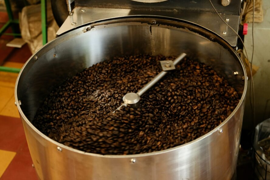 Image of a giant metal vat full of coffee beans roasting.