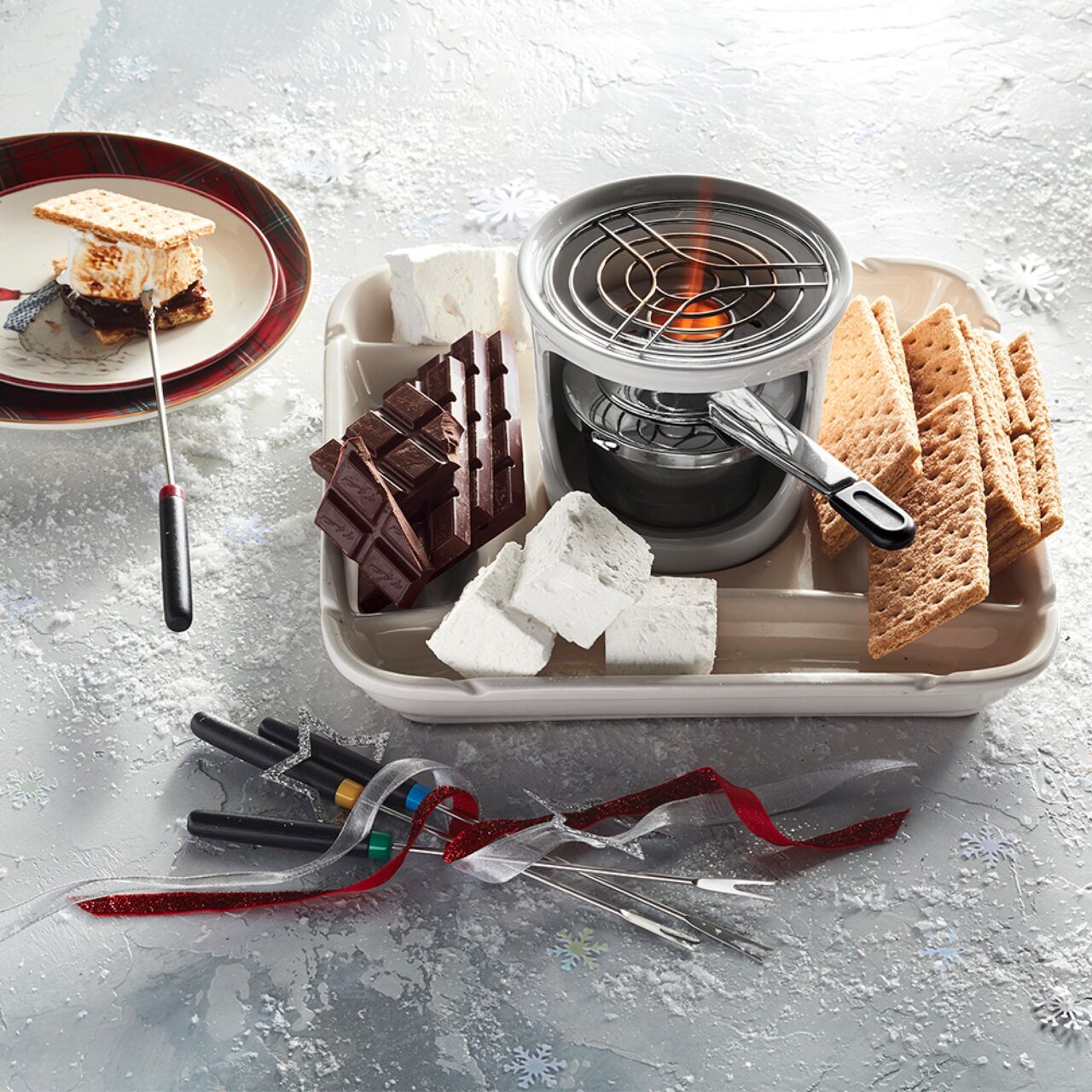 Image of the Williams Sonoma S'mores Maker shown on ice, featuring marshmallows, graham crackers, and blocks of chocolate.