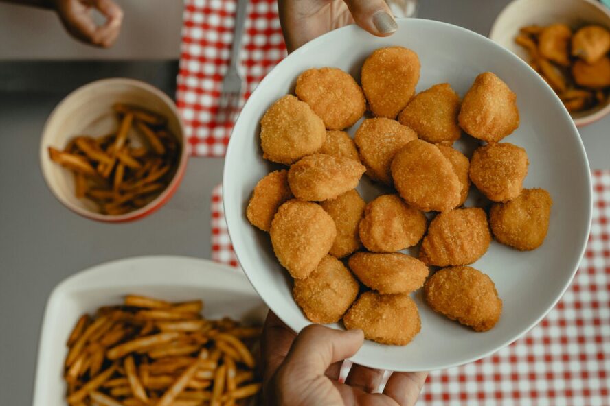 Image of a large plate full of chicken nuggets and surrounded by bowls of fries.