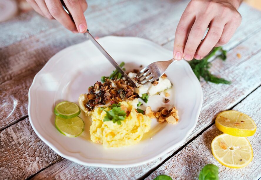Image of a plate with a lean fish served on a bed of mashed potatoes.