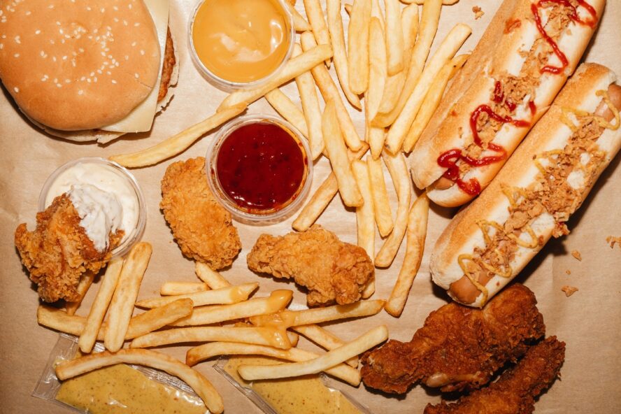 Image of a platter of ultra-processed fast foods: french fries, fried chicken, and various dips.