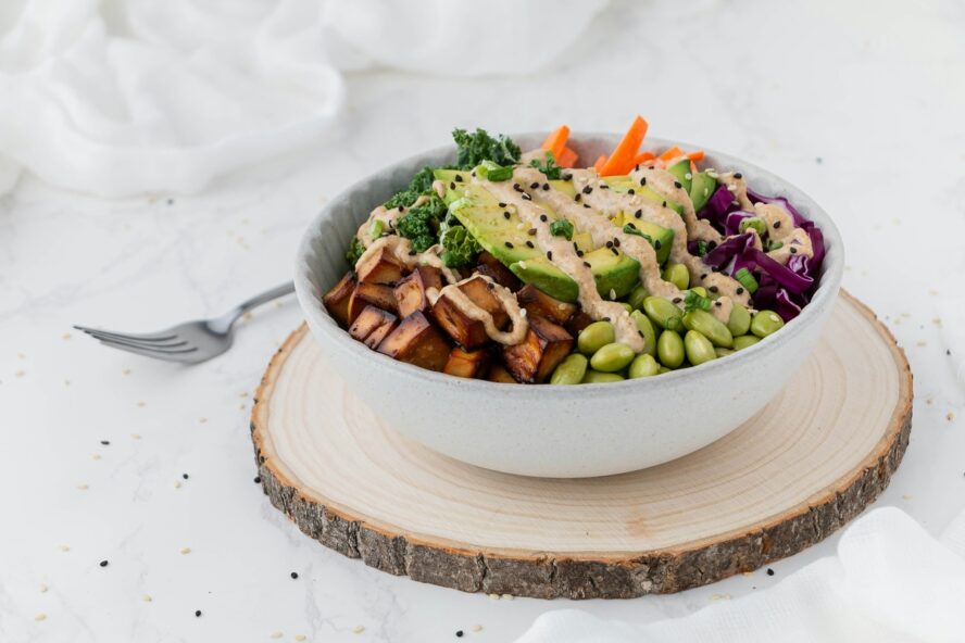 Image of a large white bowl full of salad, including avocado, green beans, tofu, and more vegetables.