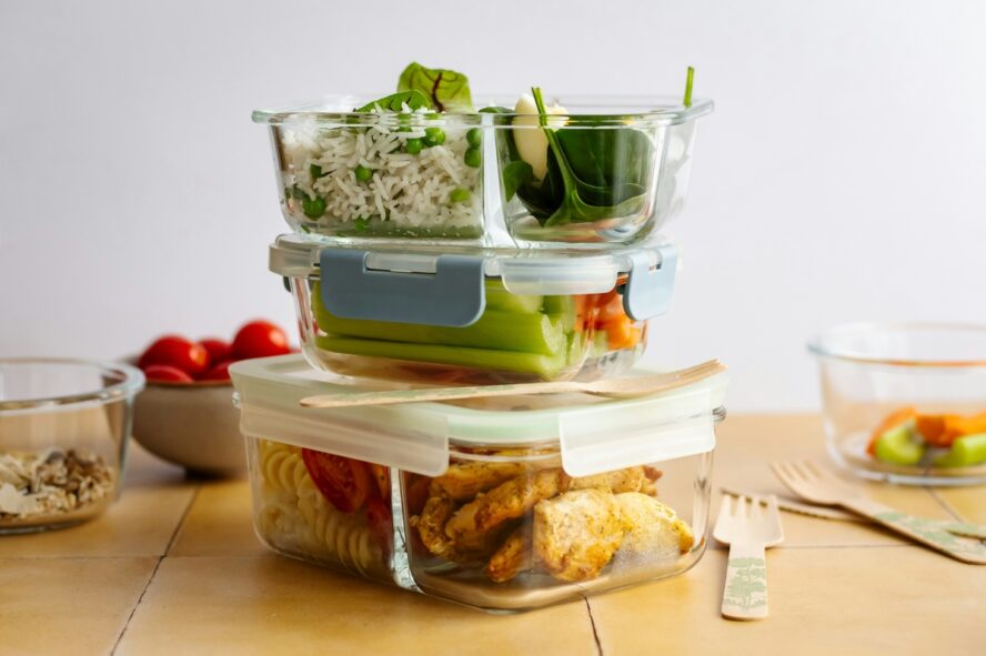 Image of three glass food storage containers stacked on top of each other full of leftover meals.