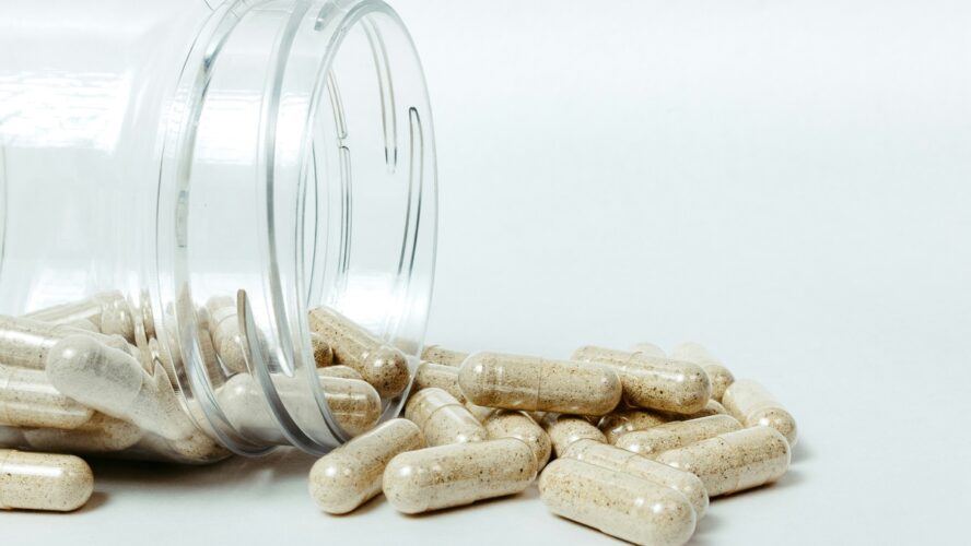 Image of a plastic jar overflowing with little probiotic supplement pills.