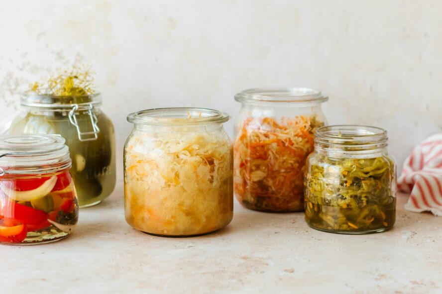 Image of several glass jars full of fermented and pickled vegetables, which are known to improve gut health.