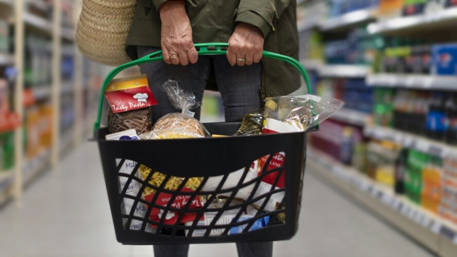 Image of a woman holding a full basket at the grocery store.