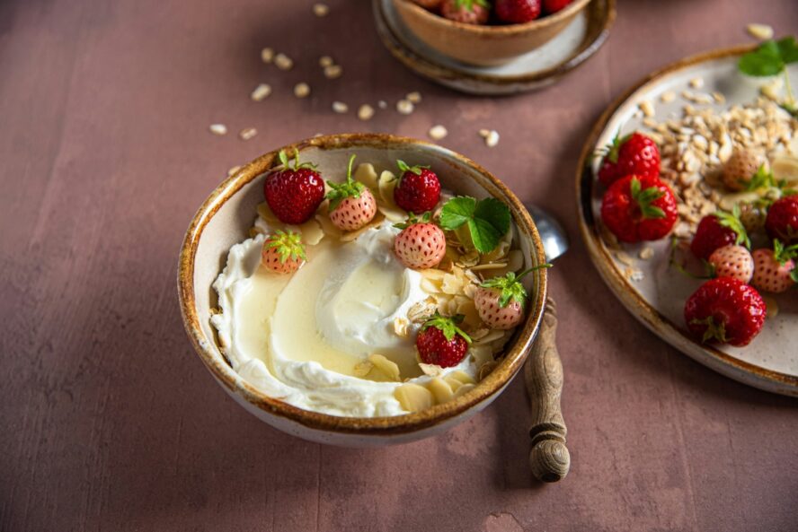 Image of a bowl of greek yogurt with honey, strawberries, and some slivered almonds.
