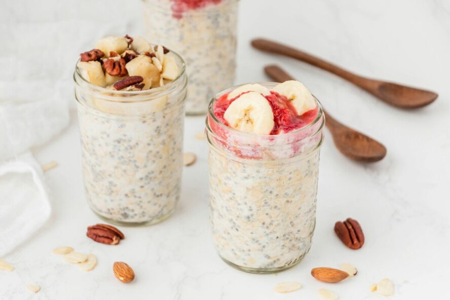 Image of three mason jars full of overnight oats and topped with various berries, nuts, and other high-fiber fruits.