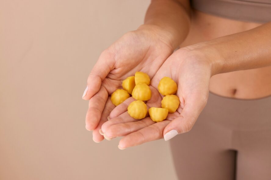 Image of a woman's hands held with open palms, filled with yellow gummy vitamins.