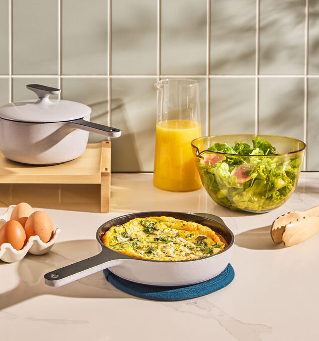 Image of a Caraway enameled cast iron skillet in gray with a full frittata, next to eggs and a bowl of salad.