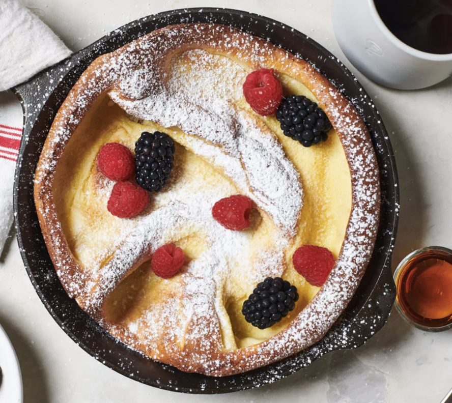 Image of a Field Company cast iron skillet, being used to make a Dutch baby topped with berries and powdered sugar.