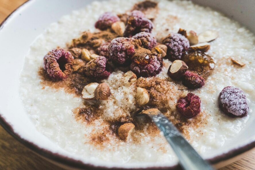 Close-up image of a bowl of appetizing oatmeal topped with cinnamon, nuts, and berries.