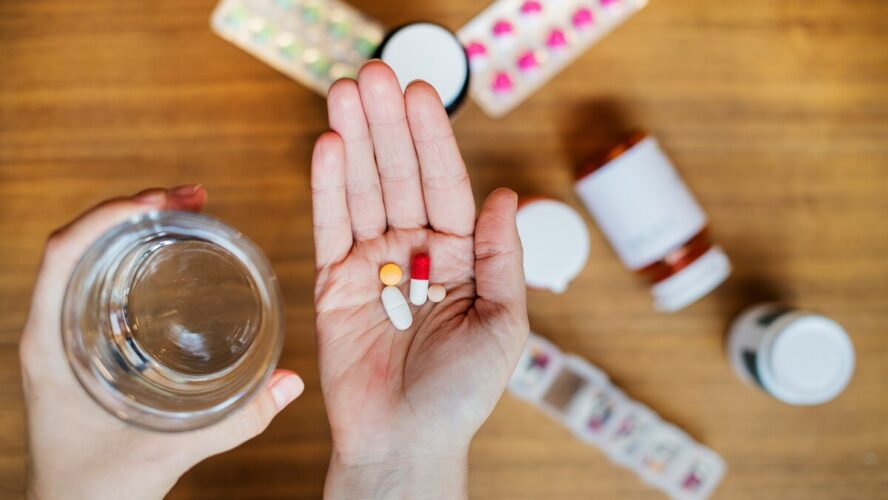 Image of a hand with a palm open and several different supplement pills in it.