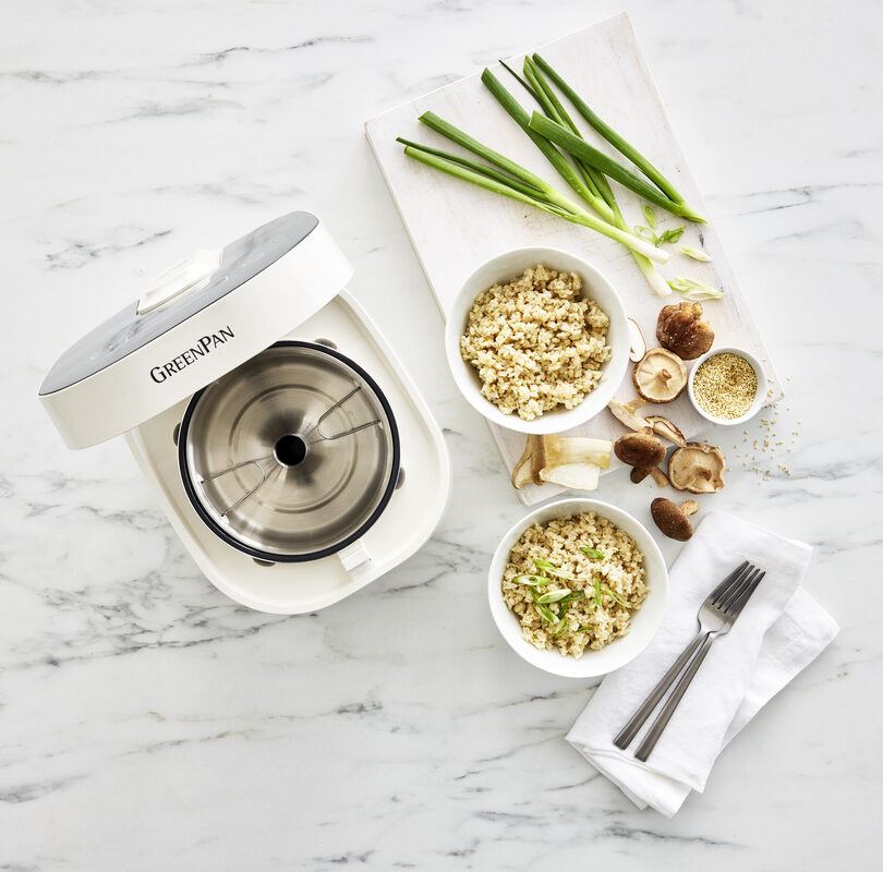 Overhead image of the GreenPan Bistro Carb Reducing rice cooker in cloud cream, highlighting the removable container beside bowls of rice with veggies.