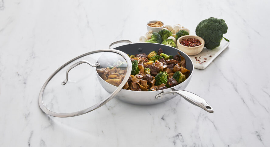 Image of the GreenPan Valencia Stainless Steel Wok with lid, full of stir-fry beef and broccoli noodles.