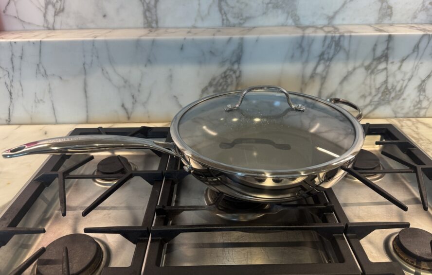 Image of the GreenPan Valencia Pro Stainless Steel Wok with lid on a gas stovetop.