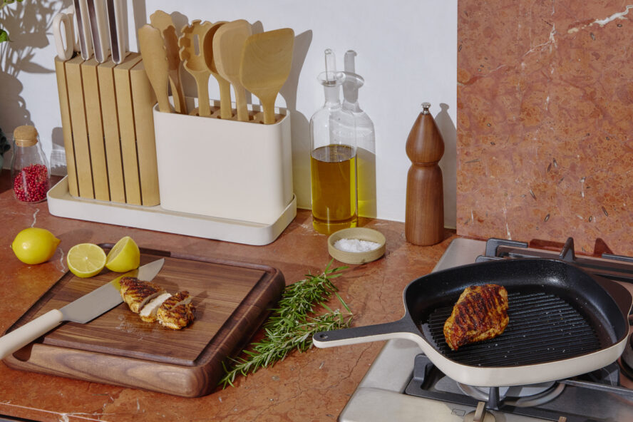 Image of a Caraway Home Prep & Serve Butcher Block in walnut on a kitchen counter next to a stovetop.