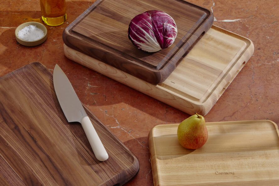 Image of several Caraway Prep & Serve Butcher blocks in maple and walnut, shown displayed on top of one another with a knife, cabbage, and pear.
