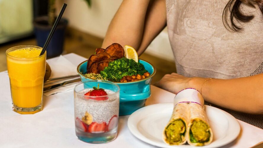 Image of someone sitting with a bowl and plate of healthy plant-based foods at the table.