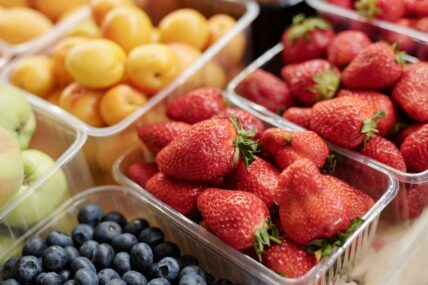 Image of several plastic containers filled with different types of fruit, including strawberries, blueberries, and nectarines.