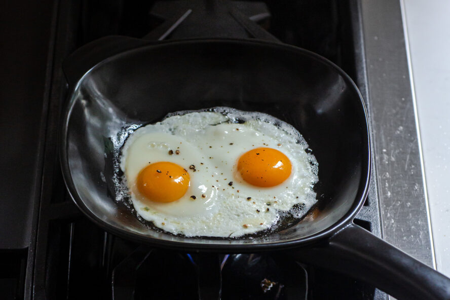 Image of two sunny side-up eggs frying in an Xtrema pure ceramic pan on the stovetop.