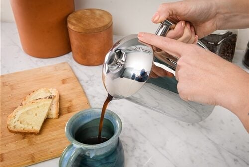 Image of the Freiling Stainless Steel French Press pouring coffee into a blue mug.