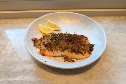 Image of two air-fried salmon fillets encrusted in a parmesan-garlic breadcrumb, served with a slice of lemon.