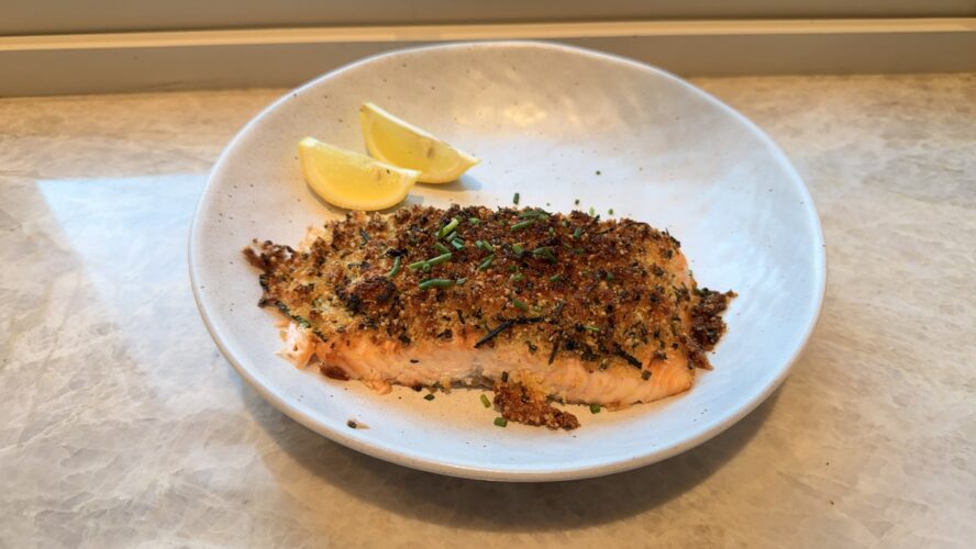 Image of two air-fried salmon fillets encrusted in a parmesan-garlic breadcrumb, served with a slice of lemon.