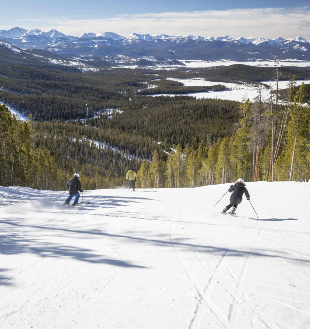 Image of three skiiers making their way down a snowy mountain.