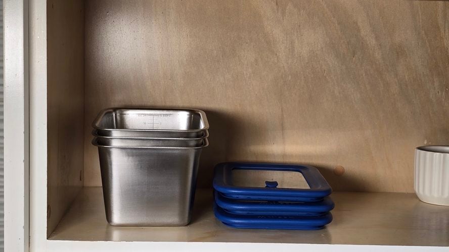 Image of three large Misenware containers stacked on a shelf in a cabinet next to three accompanying lids.